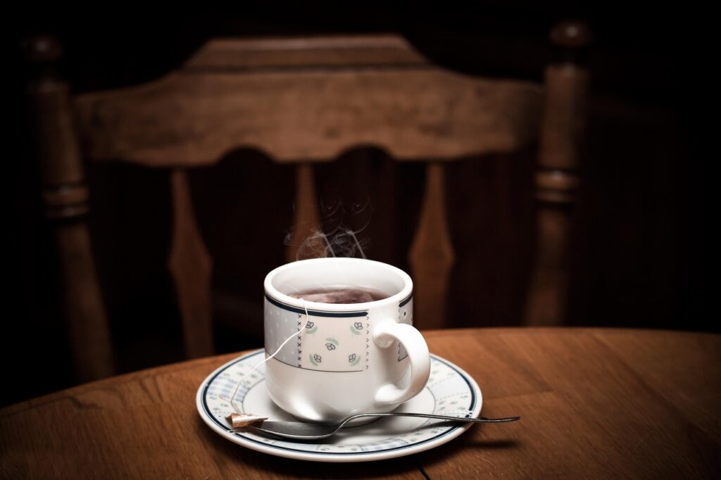 Gőzölgő csésze tea egy sötét asztalon, mögötte üres szék: a kimondatlan gyász a családban
